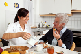 Caregiver accompanying a senior during her meal