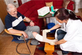 Caregiver changing the wound dressing of a senior