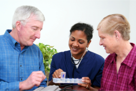 Caregiver giving medication to a senior couple