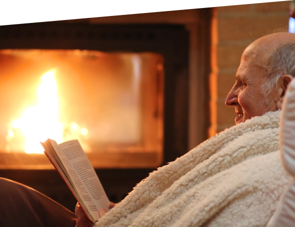 Male senior reading a book near a fireplace